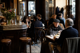 Interior acolhedor de um bistrot francês tradicional, com balcão de madeira, pratos simples e clientes conversando