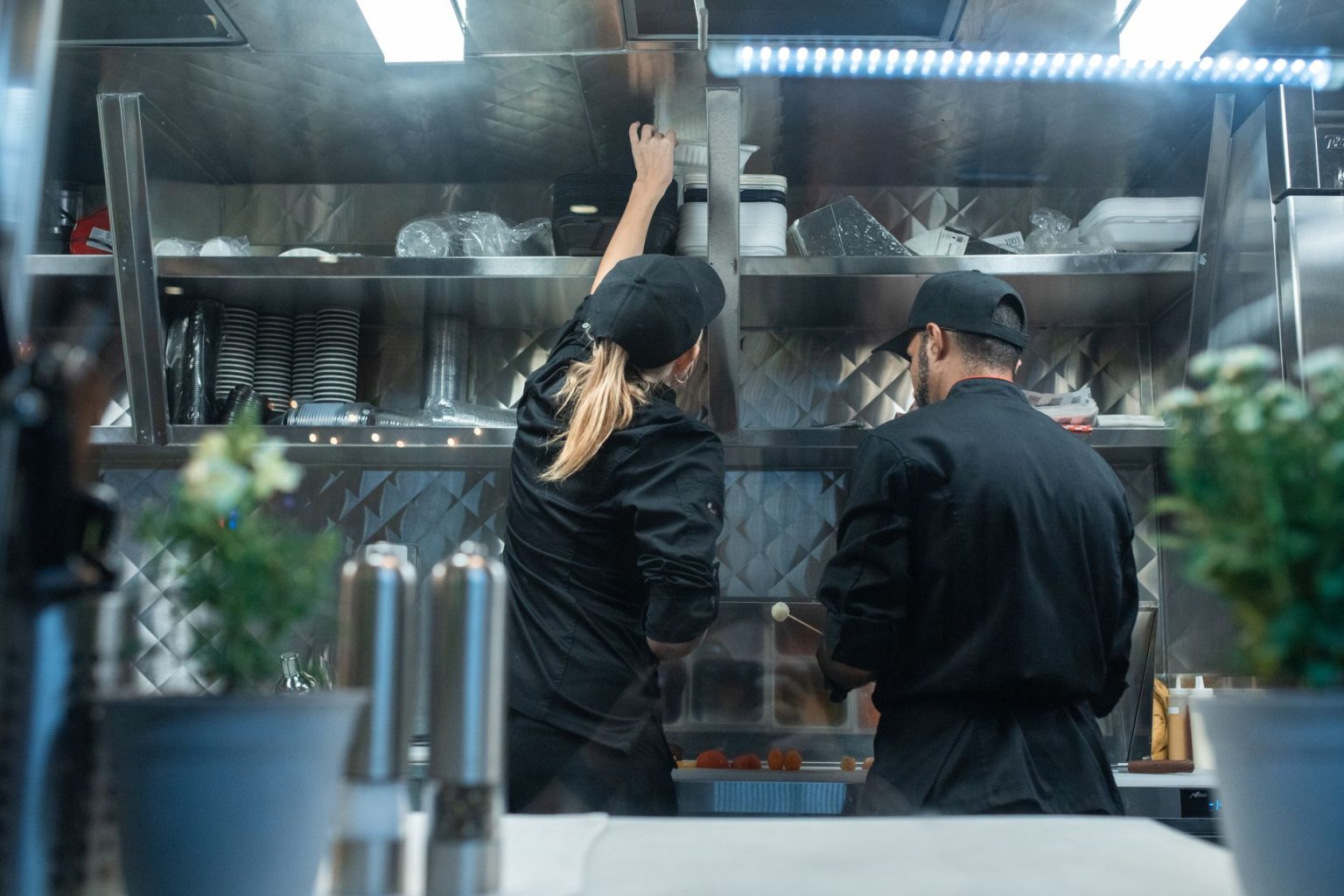 Dois chefs trabalham juntos na preparação de pratos em uma cozinha profissional.