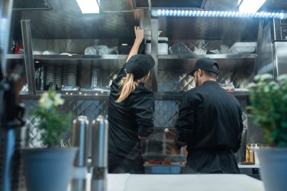Dois chefs trabalham juntos na preparação de pratos em uma cozinha profissional.