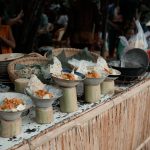 Mercado movimentado de comida de rua com barracas que exibem pratos da culinária asiática.