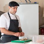Chef prepara um prato em uma cozinha profissional.