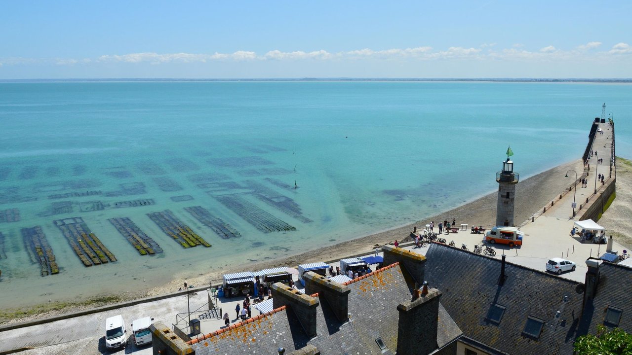Vista aérea da costa de Cancale, na Bretanha, com viveiros de ostras e um farol sob céu claro