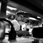 Chefs colaboram no preparo de alimentos em uma cozinha profissional.