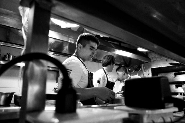 Chefs colaboram no preparo de alimentos em uma cozinha profissional.